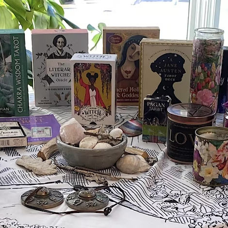 assortment of tarot cards, books and crystals on a tabletop.